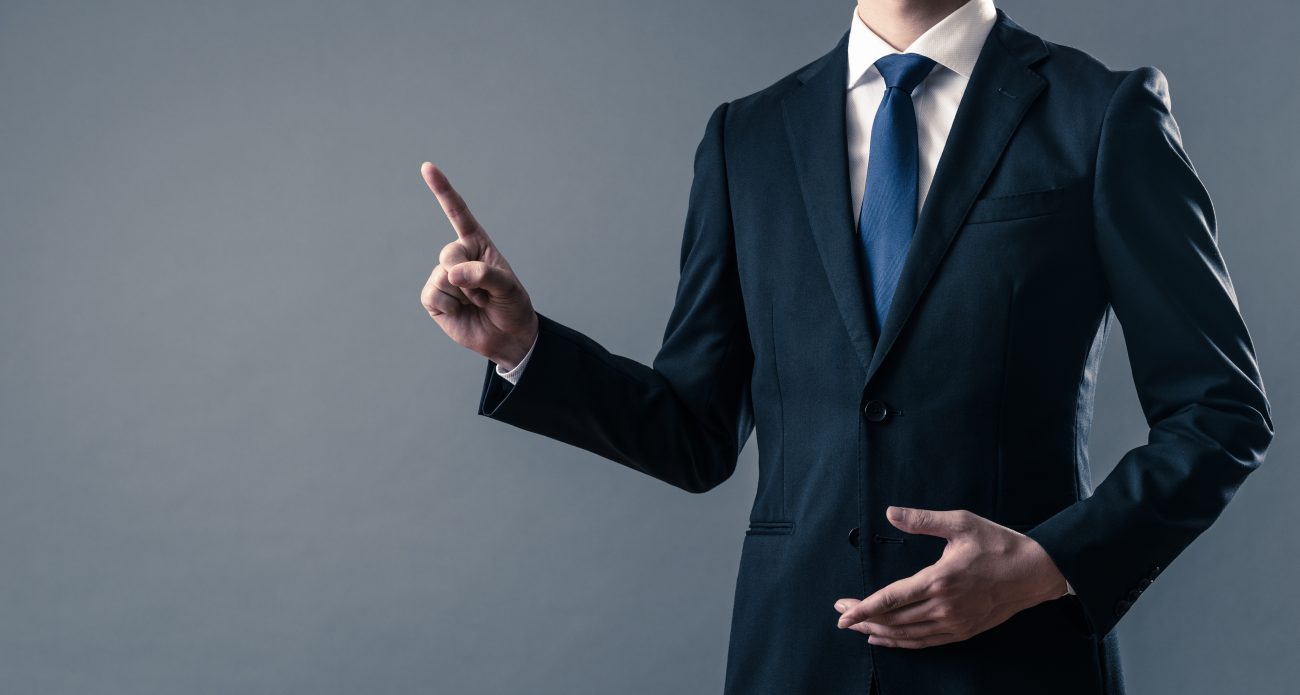 指をさしているスーツを着た男性