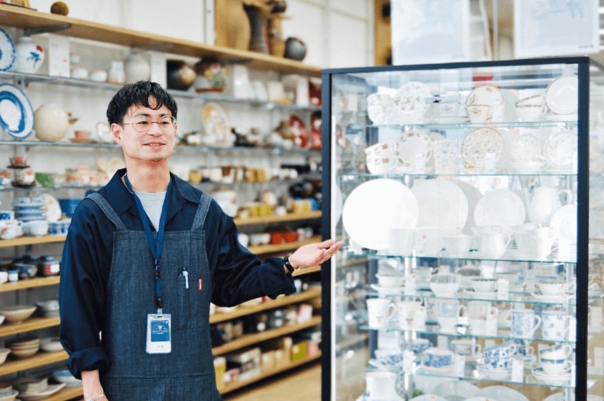 日用品売り場を紹介する男性店員
