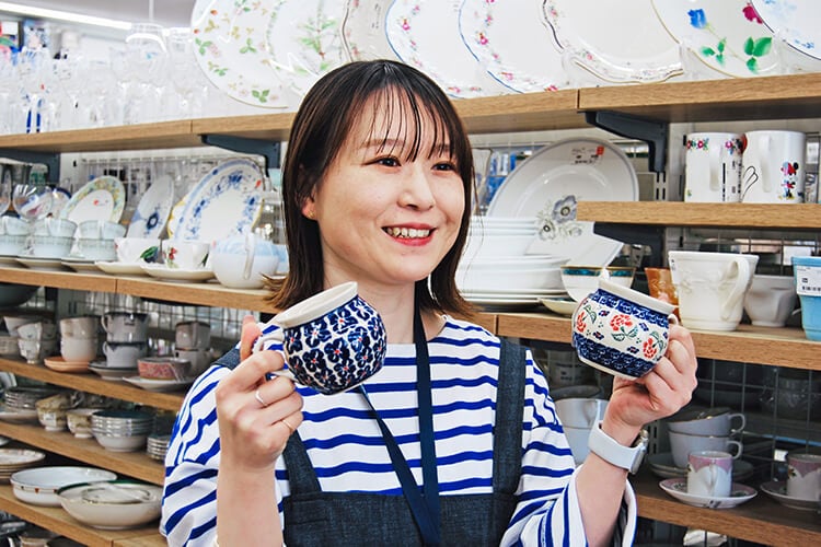 食器を手に取りながら笑顔で話すスタッフ