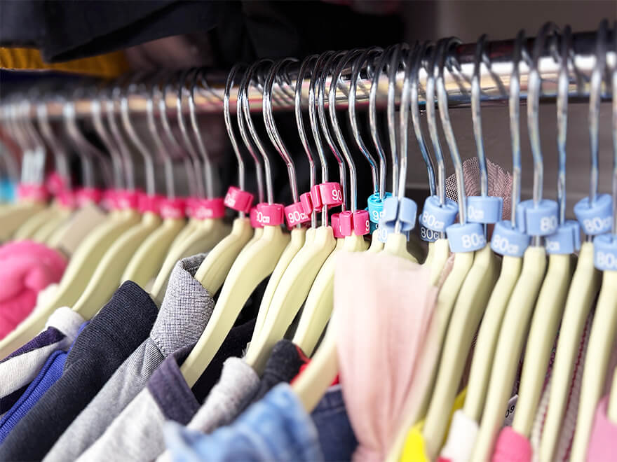 サイズチップ（80, 90cmなど）が付いたハンガーにずらりと並ぶ、買取・販売中の子供服