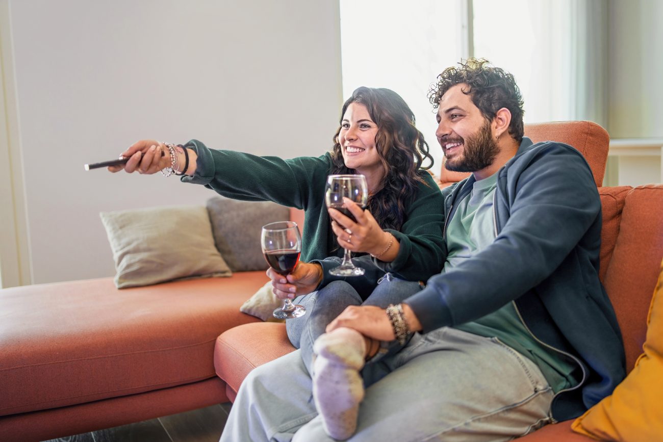 お酒を飲みながらソファに座っている男女