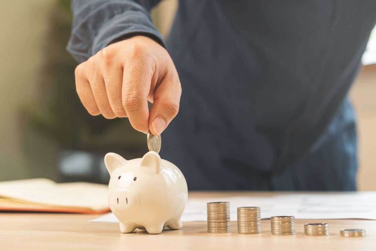 貯金箱にコインを入れようとしている男性